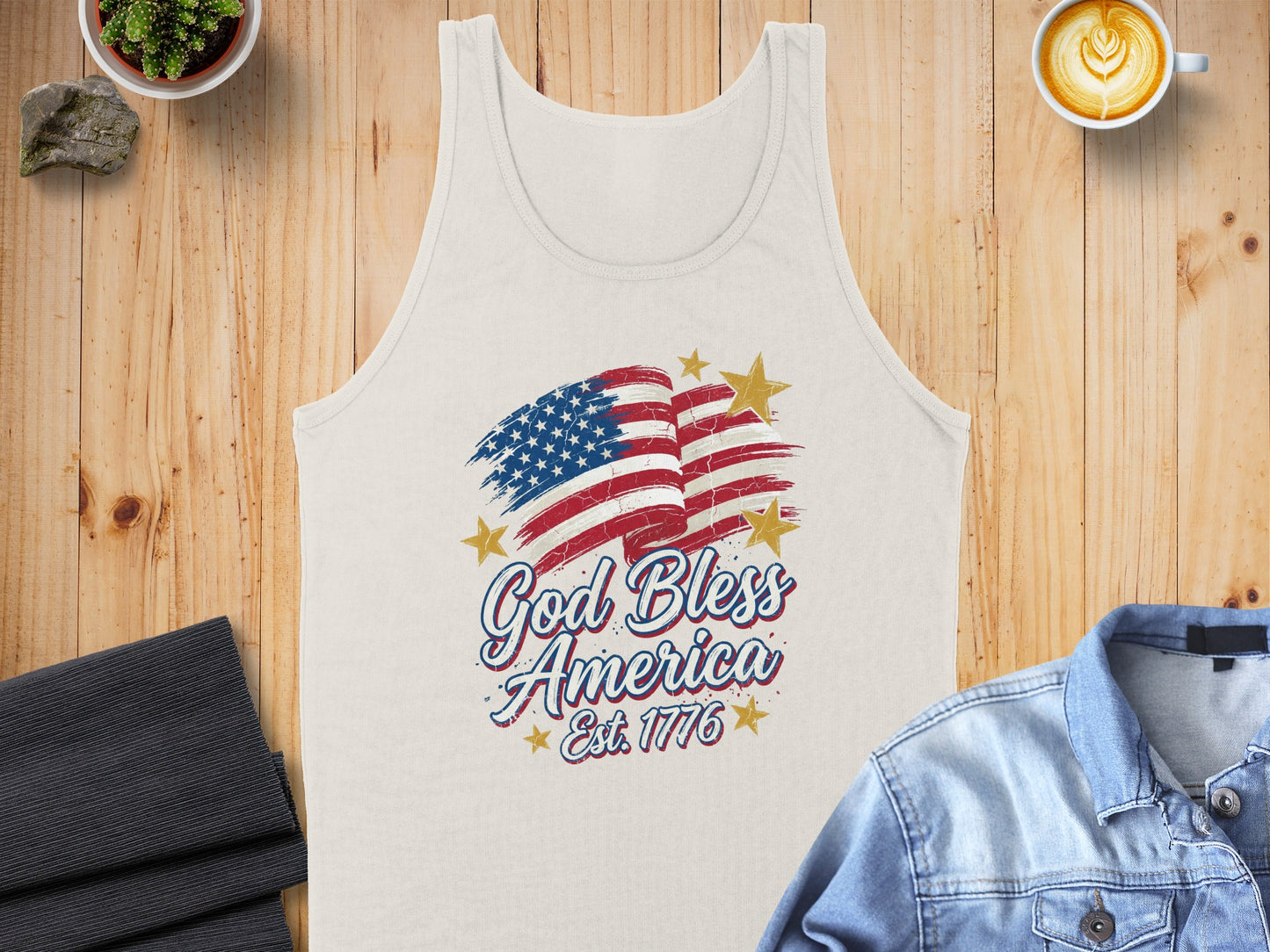 Cream tank top with distressed American flag and "God Bless America Est. 1776" text.