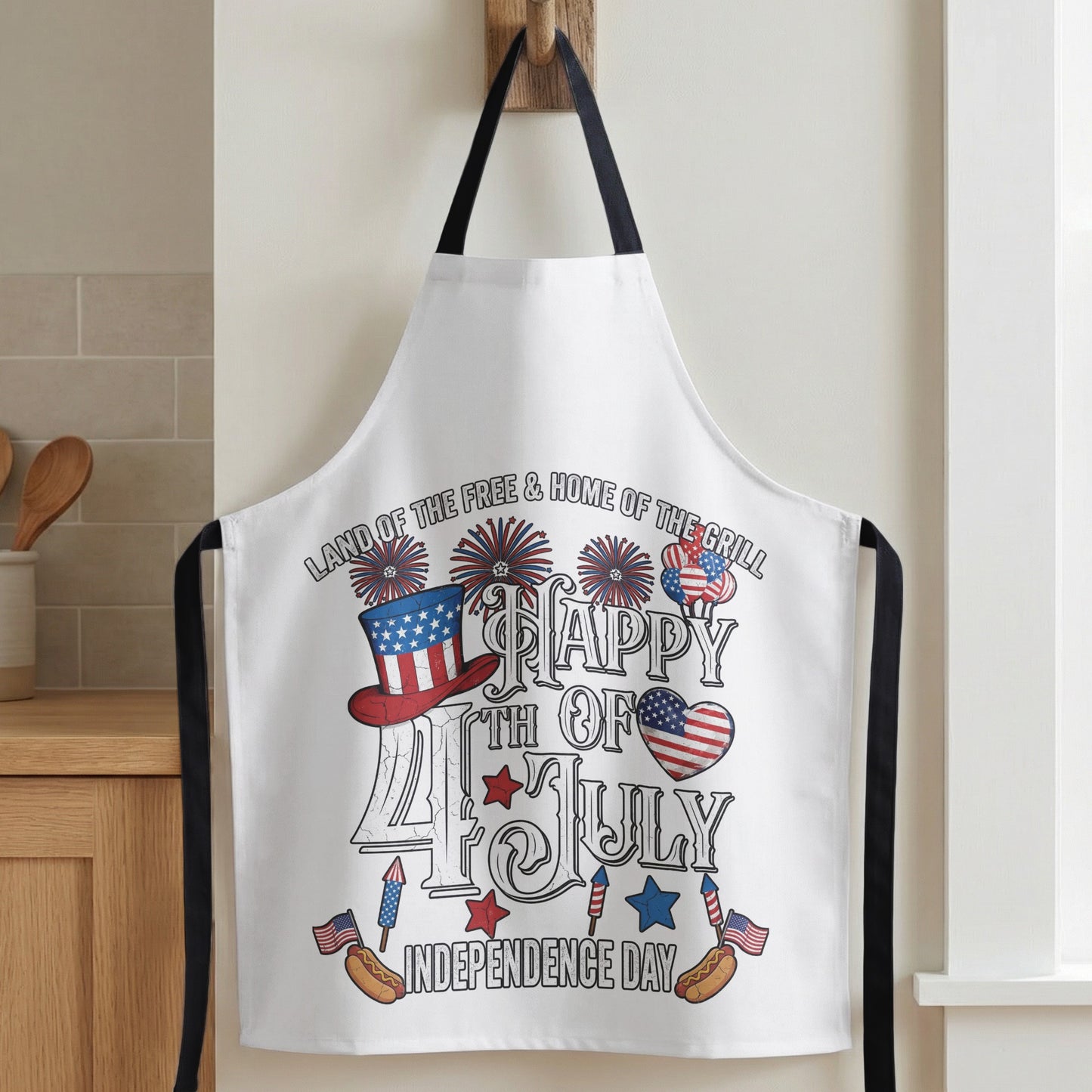 White apron with fireworks, patriotic hat, hot dogs, and "Happy 4th of July Independence Day."