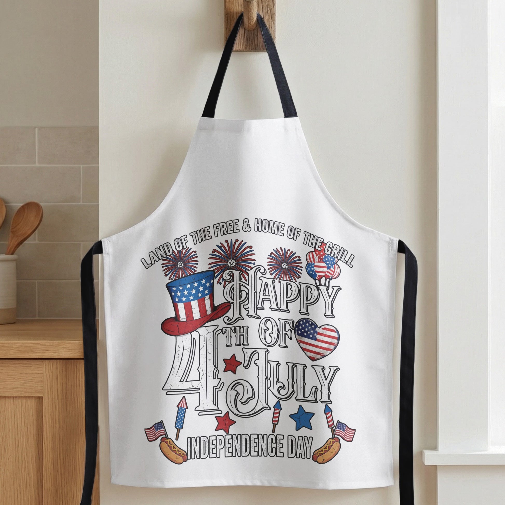 White apron with fireworks, patriotic hat, hot dogs, and "Happy 4th of July Independence Day."