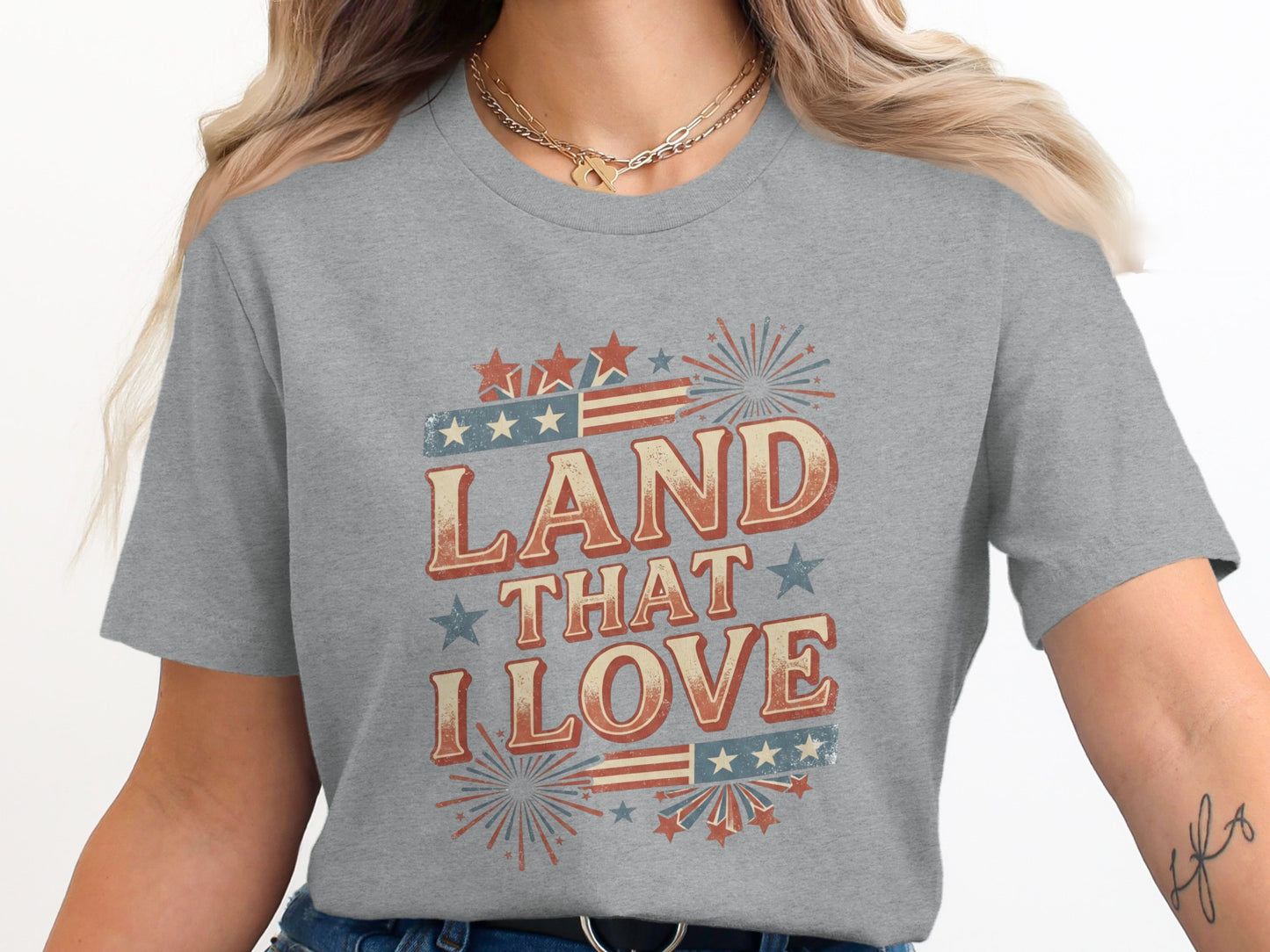 Grey t-shirt with "Land That I Love" text, fireworks, and stars.