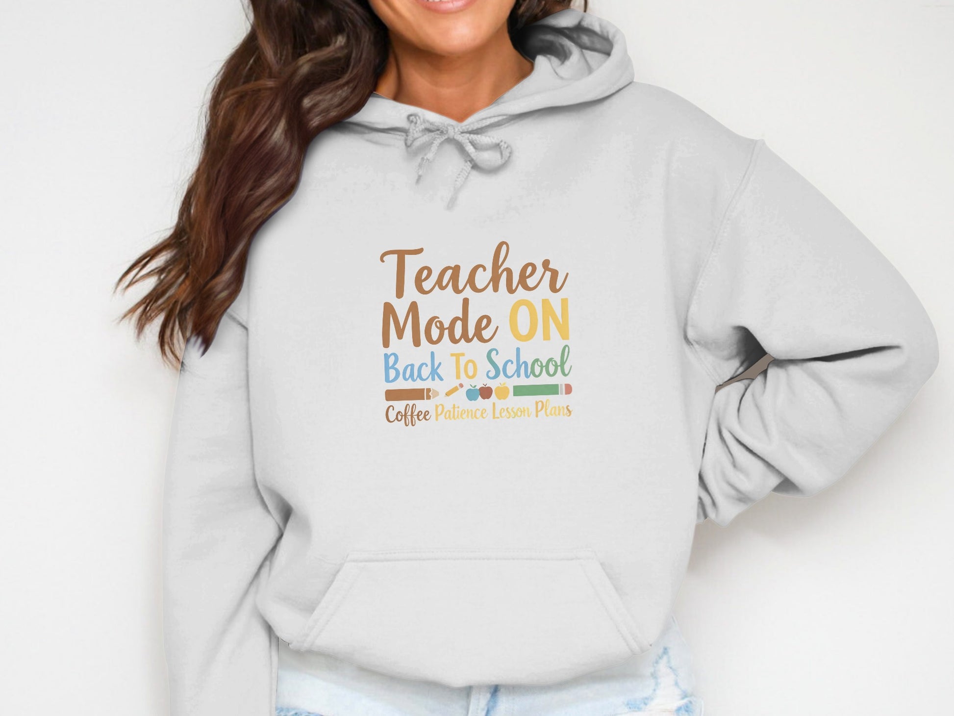 White hoodie with "Teacher Mode ON Back To School Coffee Patience Lesson Plans" text.