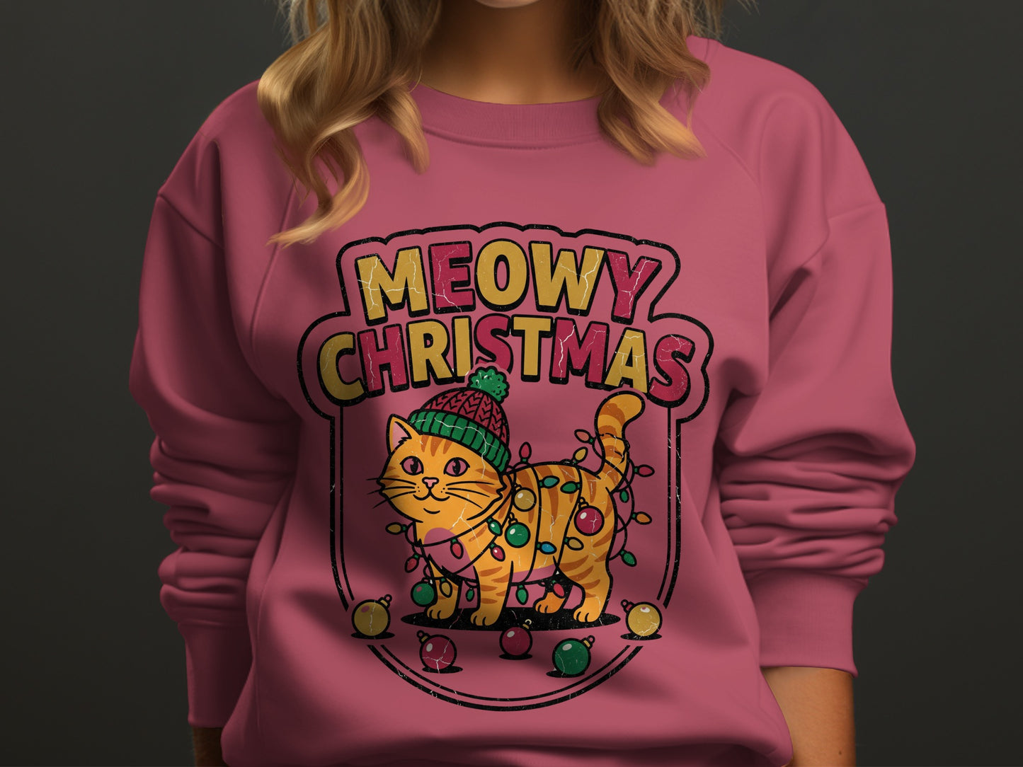 Pink sweatshirt with a cartoon cat entangled in Christmas lights and the text "Meowy Christmas".