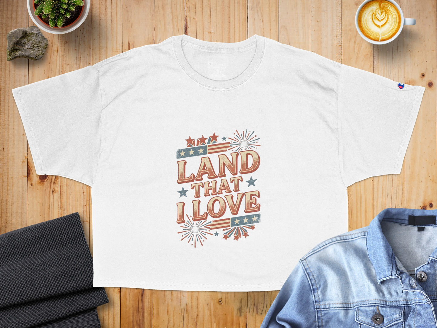 White t-shirt with retro text "Land That I Love" and American flag design.