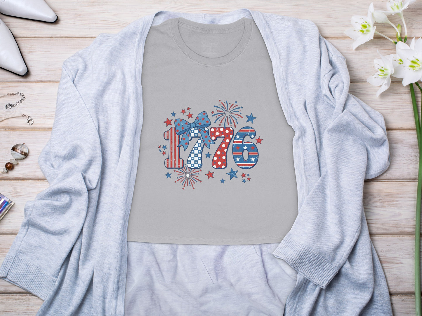Gray t-shirt with patriotic "1776" graphic featuring fireworks, stars, and bow.