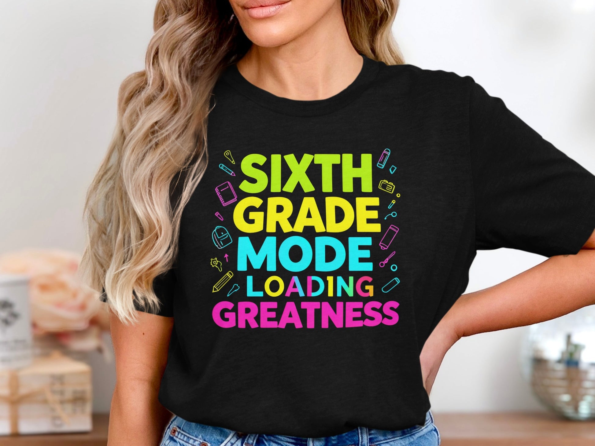 Black t-shirt with "Sixth Grade Mode Loading Greatness" text and school supplies.