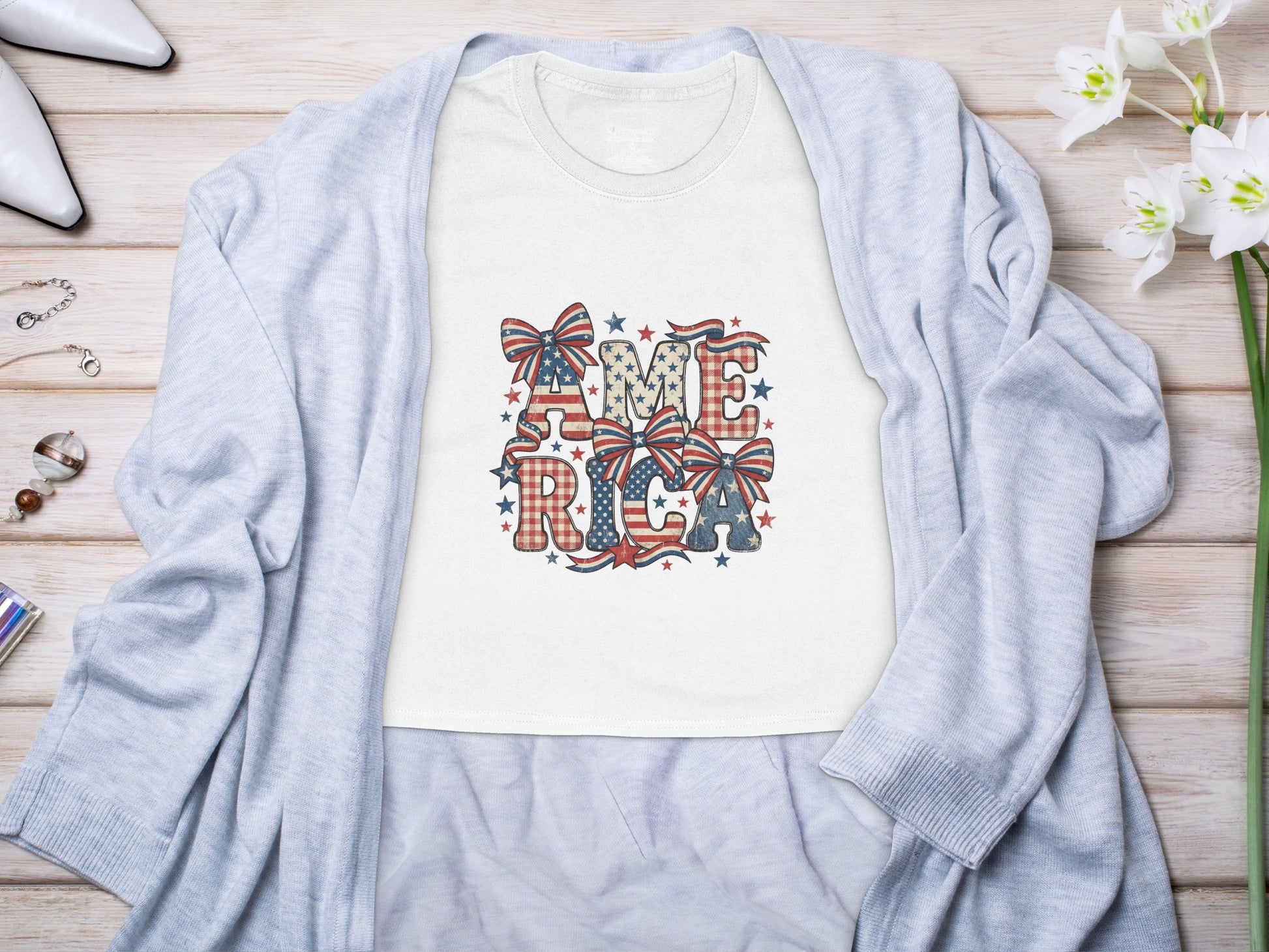 White t-shirt with "AMERICA" in patriotic pattern letters and bows.