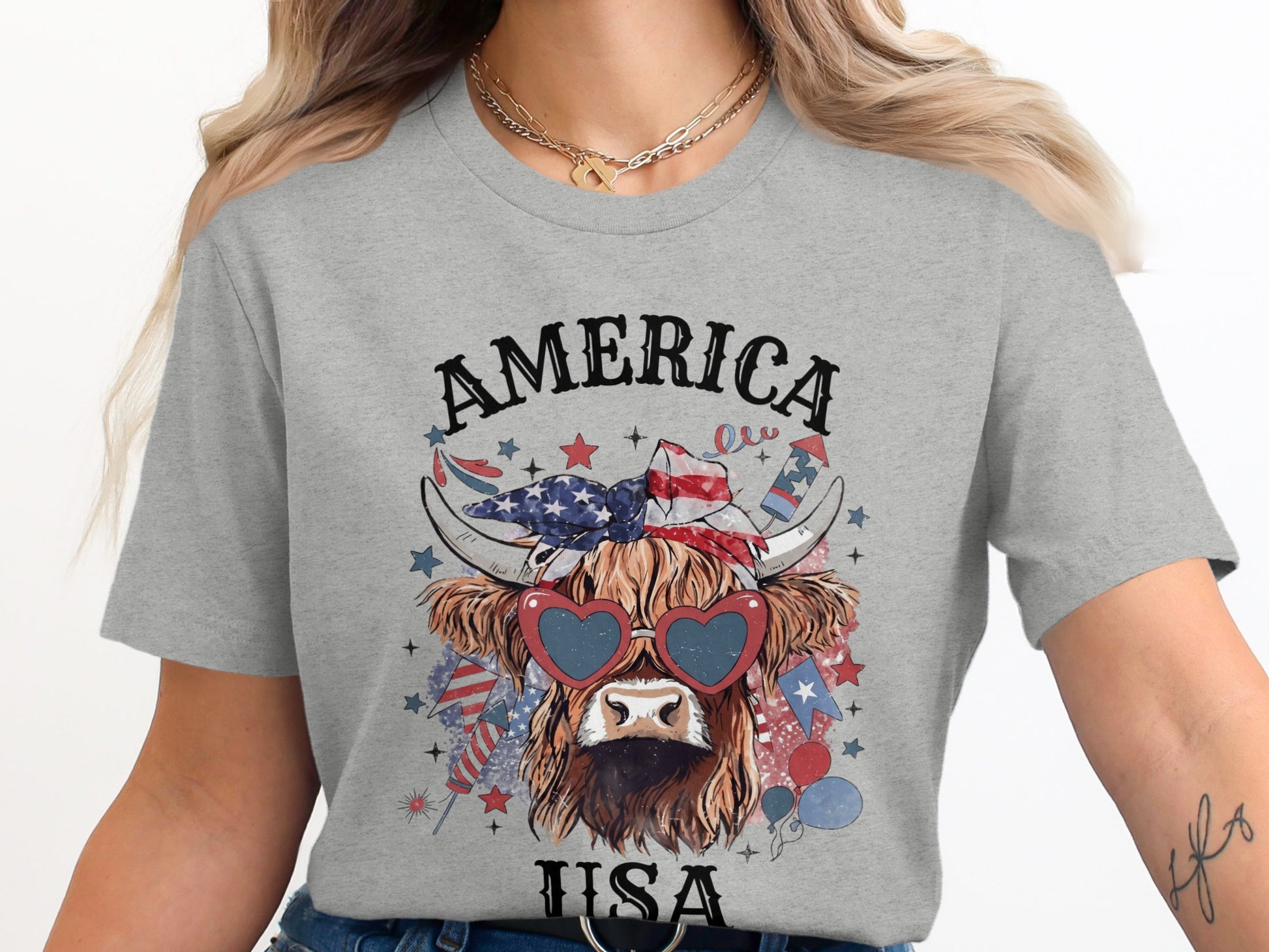 Highland cow wearing heart sunglasses and a USA bandana on a grey t-shirt.