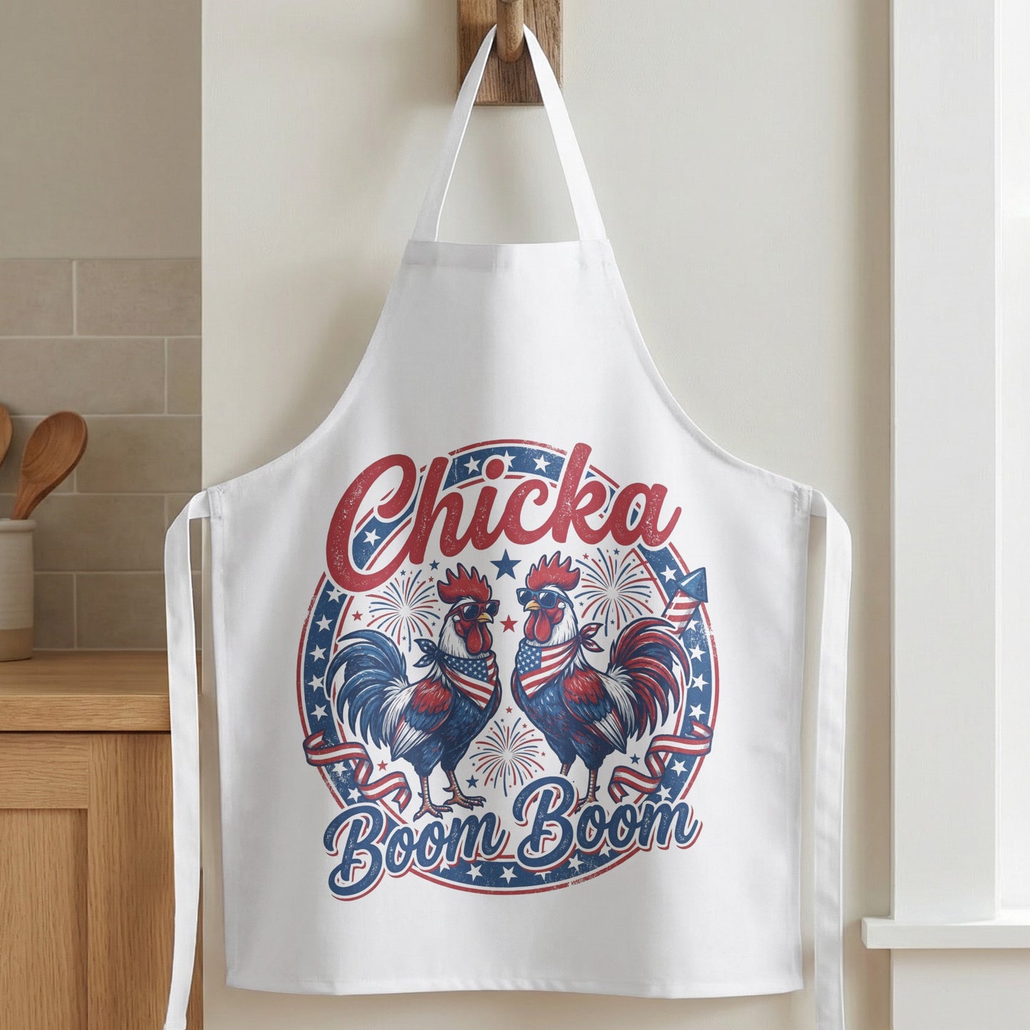 White apron with two roosters in patriotic bandanas and sunglasses, text "Chicka Boom Boom."