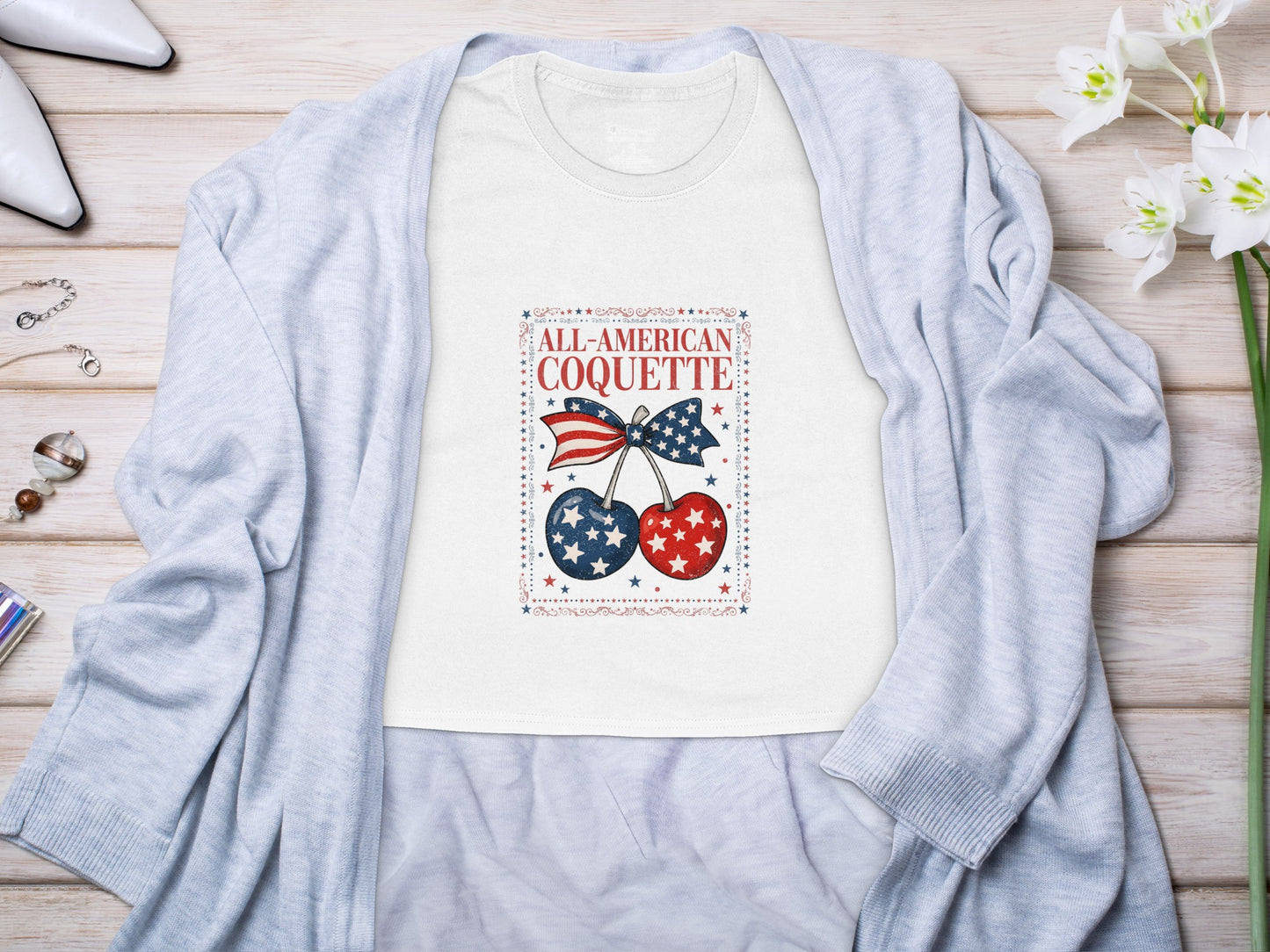 White t-shirt with "All-American Coquette" text and patriotic cherries graphic.