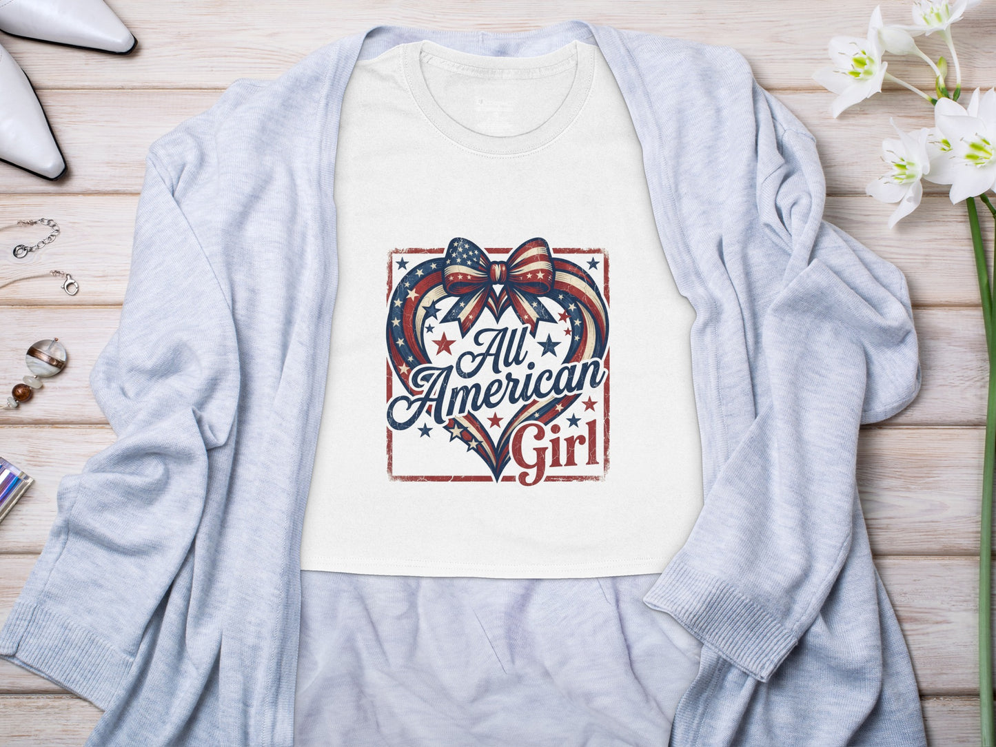 White t-shirt with "All American Girl" design featuring a patriotic heart and bow.