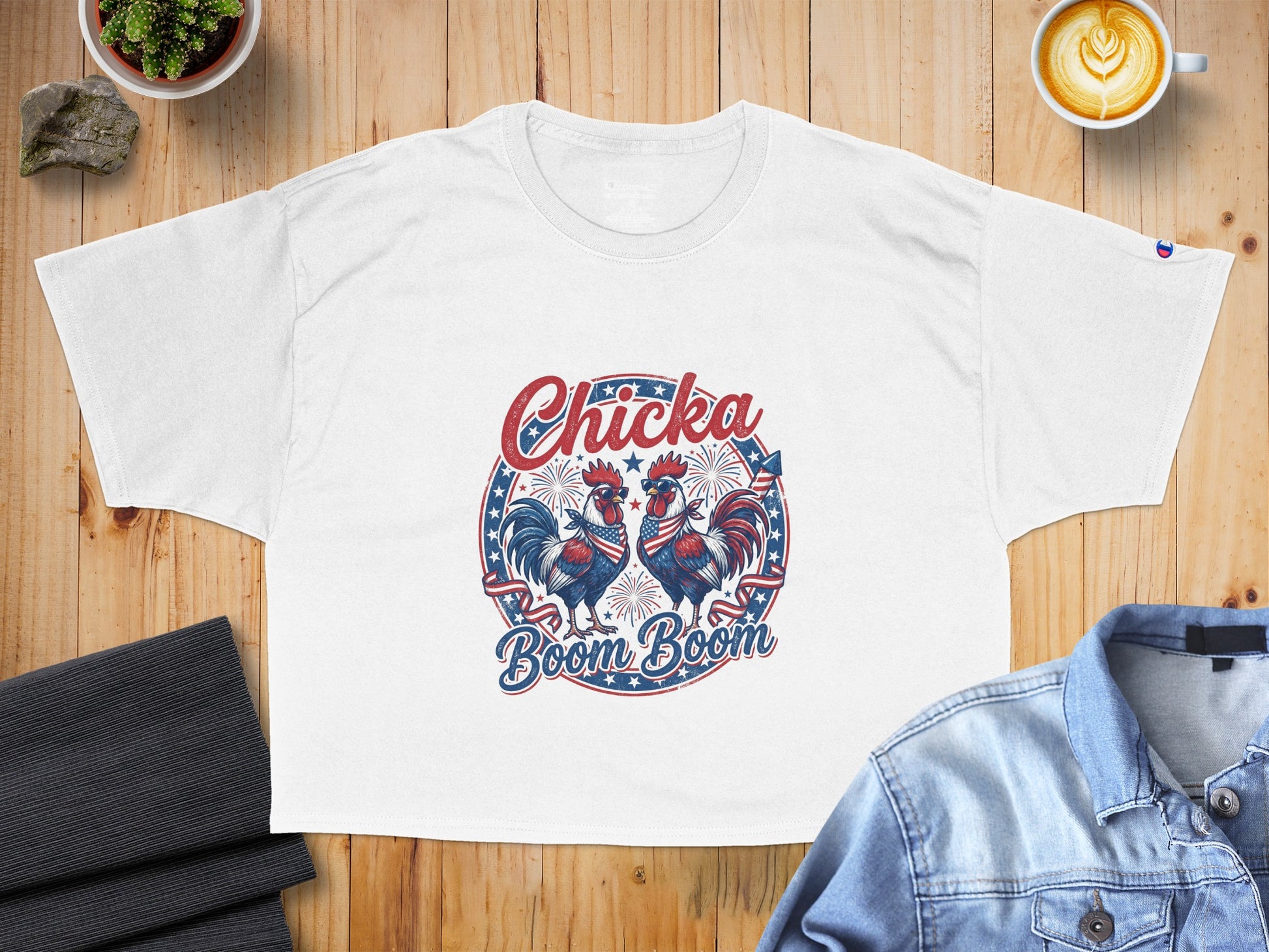 White t-shirt with a circular graphic of two roosters wearing bandanas and sunglasses, featuring fireworks and patriotic text.