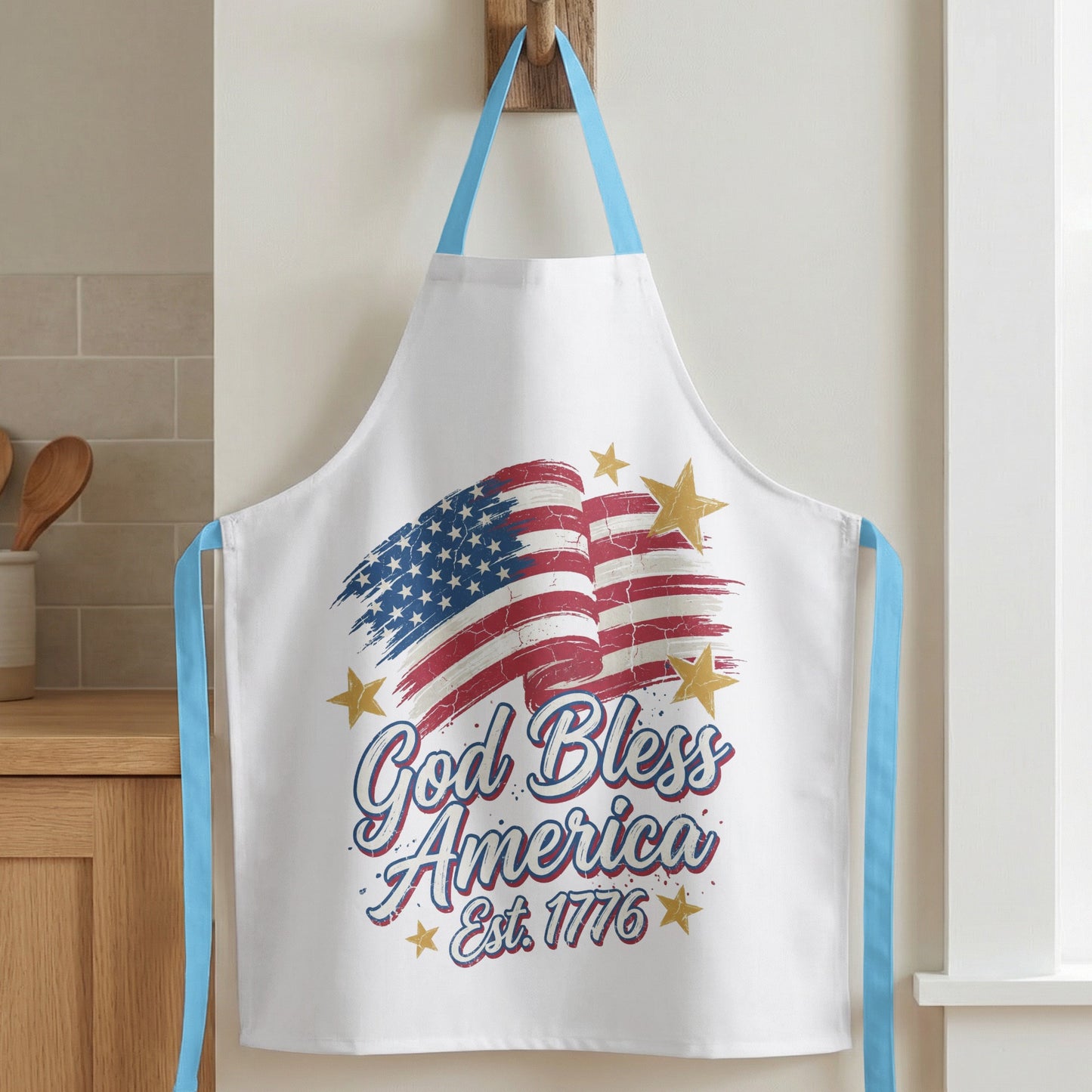 White apron with distressed American flag graphic and "God Bless America Est. 1776" text.
