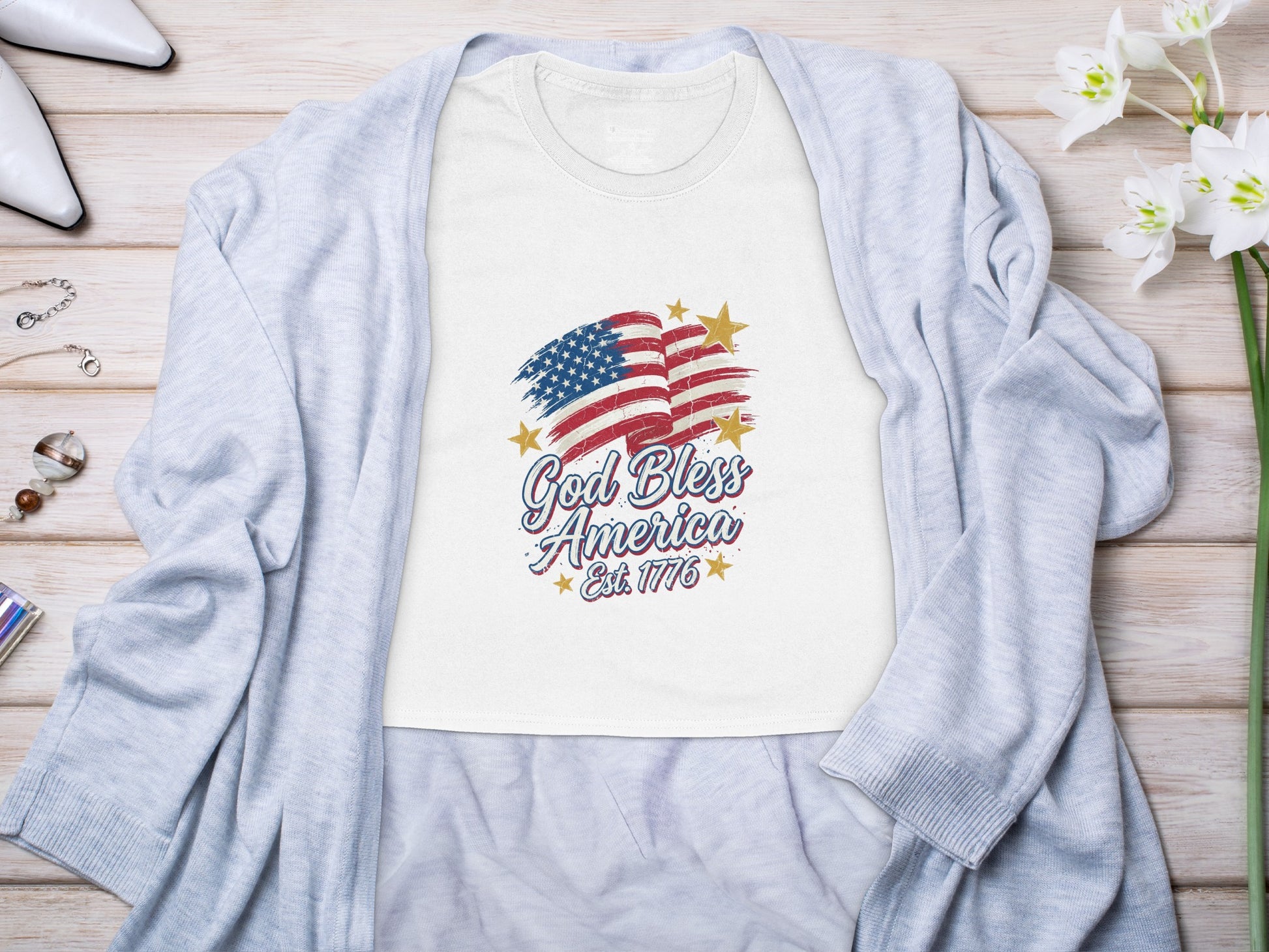 White t-shirt with American flag graphic and "God Bless America Est. 1776" text.