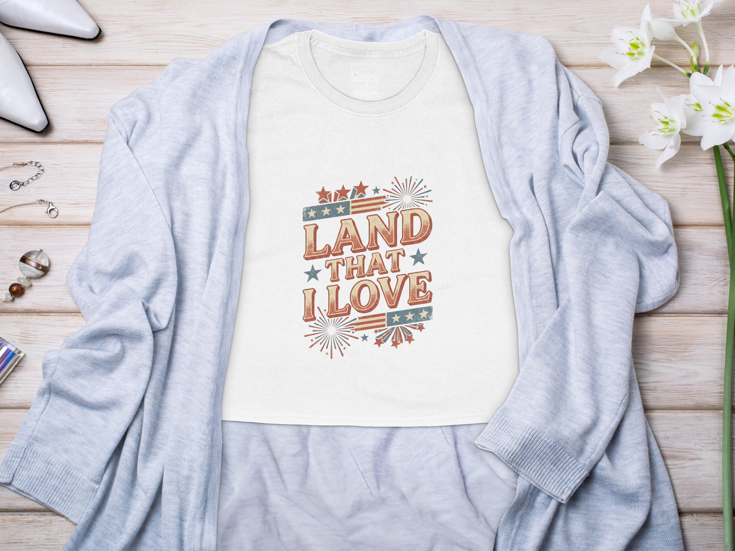 White t-shirt with "Land That I Love" patriotic graphic design.