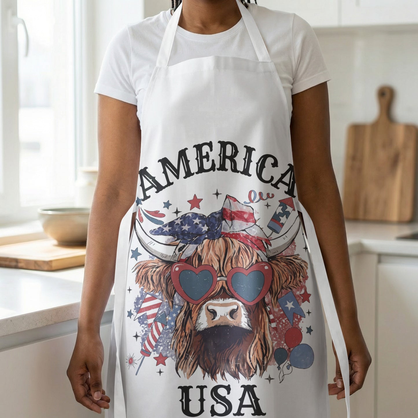 White apron with a Highland cow wearing heart sunglasses and patriotic graphics.