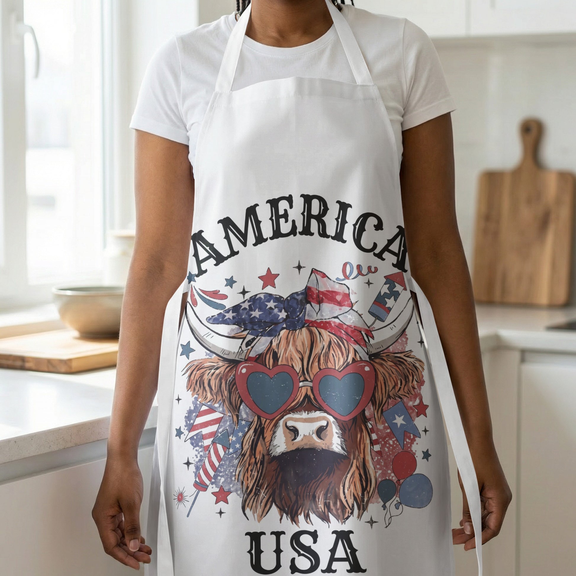 White apron with a Highland cow wearing heart sunglasses and patriotic graphics.
