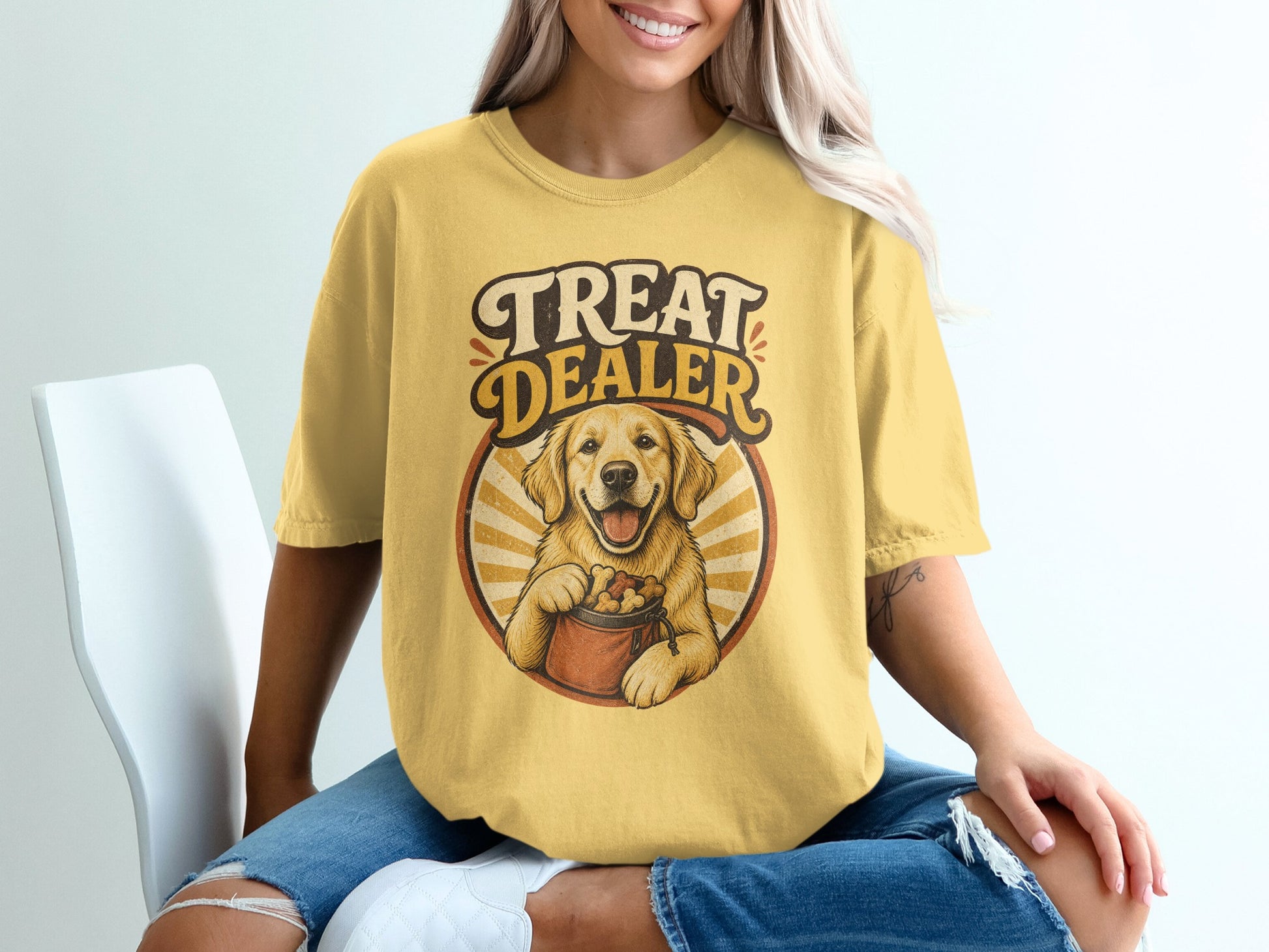Golden retriever on yellow t-shirt with text "TREAT DEALER" and dog treats.