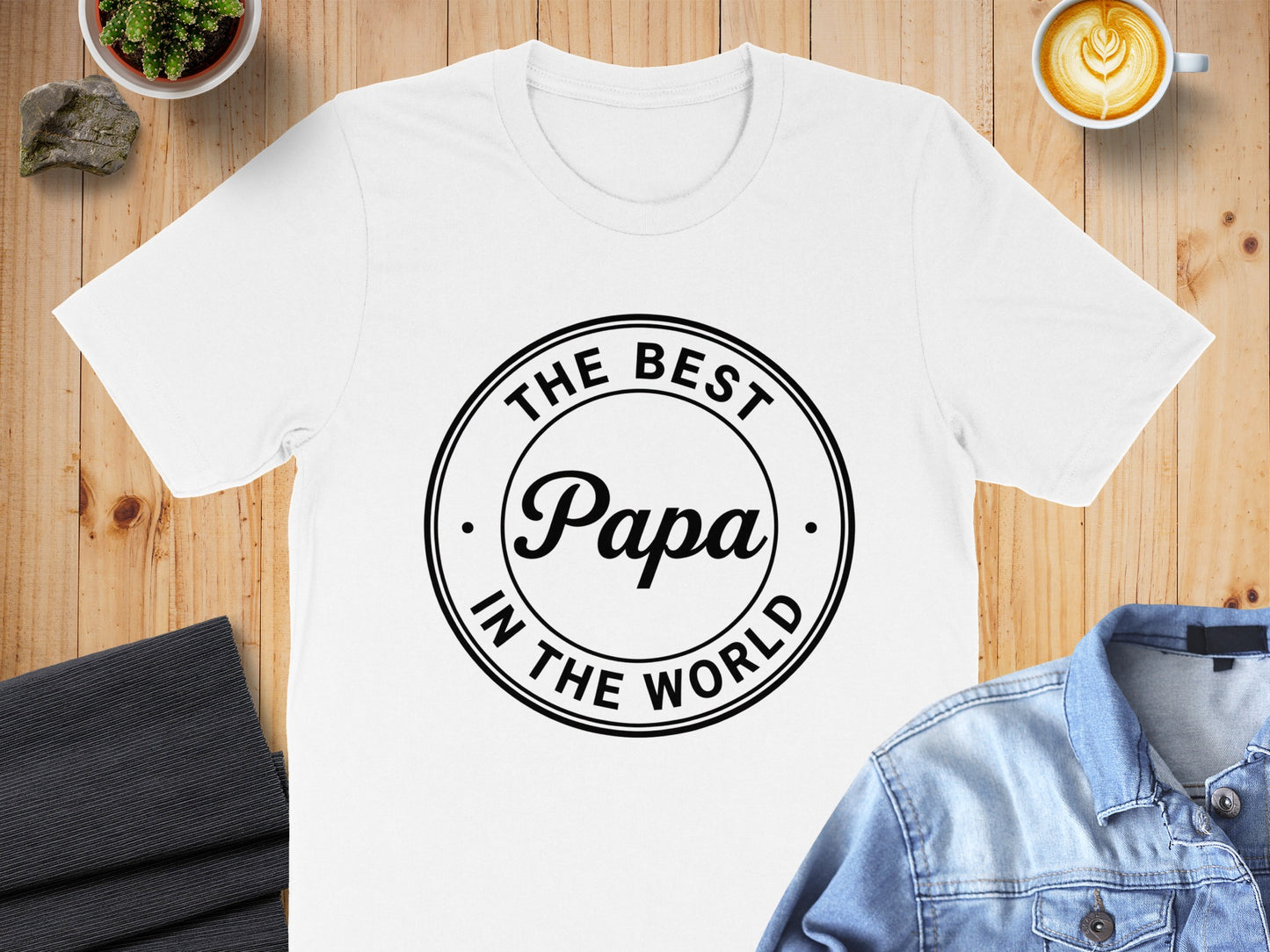 White t-shirt with black text "The Best Papa In The World" in a circular design.