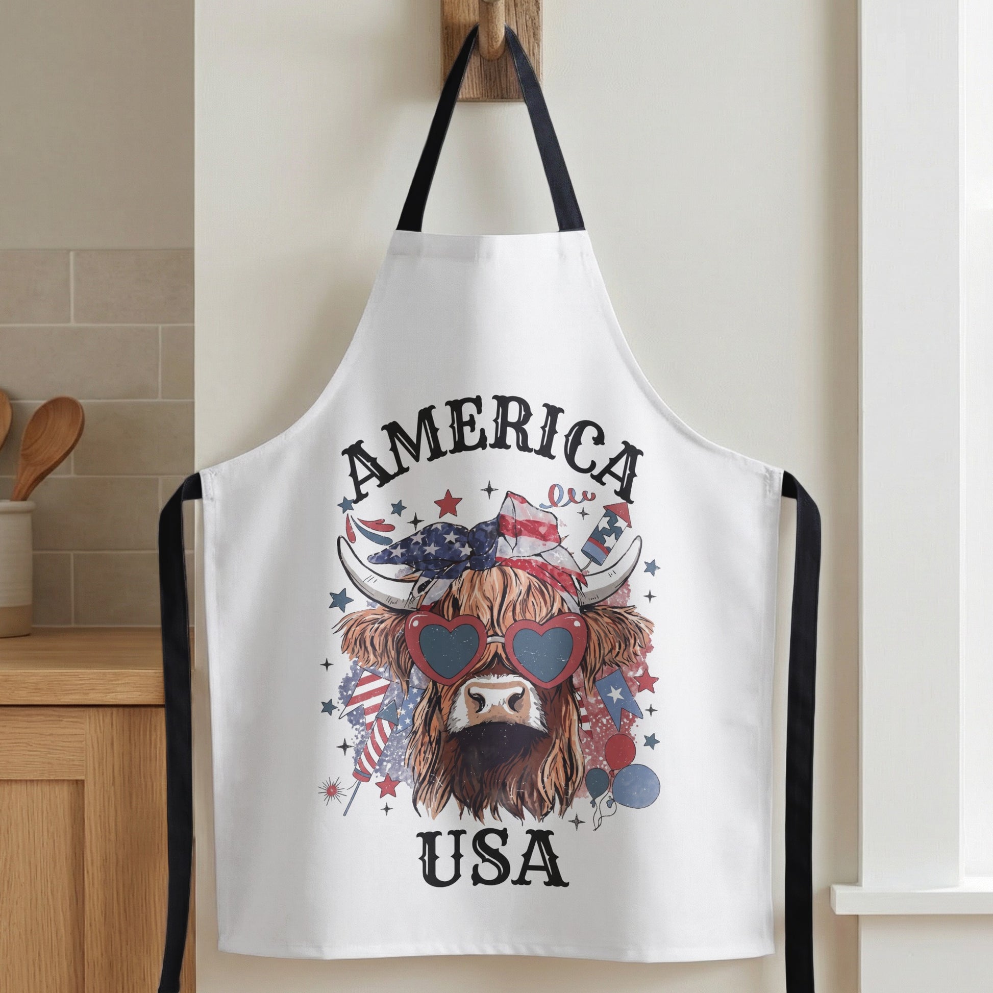 White apron with Highland cow graphic, heart sunglasses, and "America USA" text.