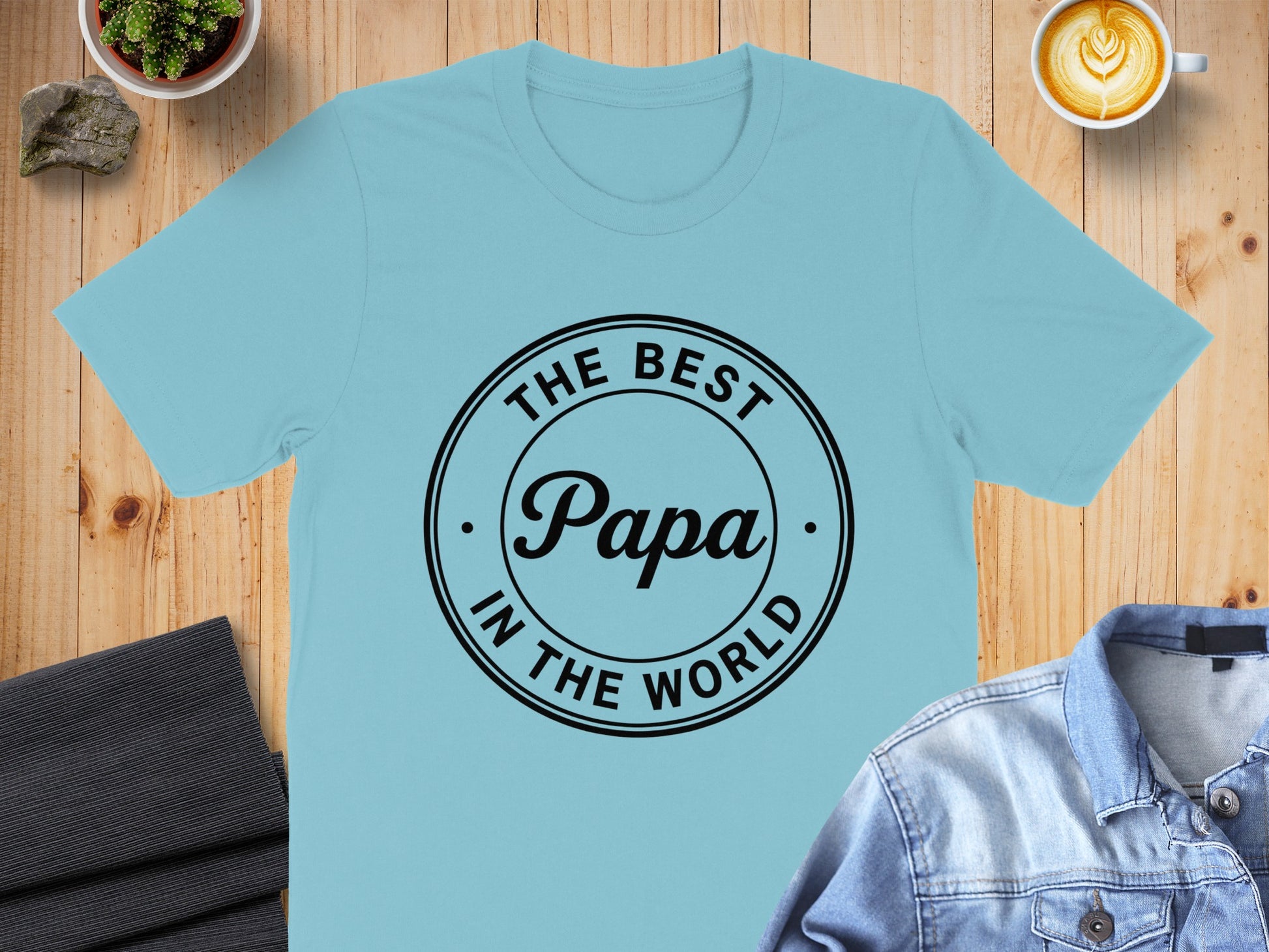 Light blue t-shirt with black text "The Best Papa In The World" on a circle.