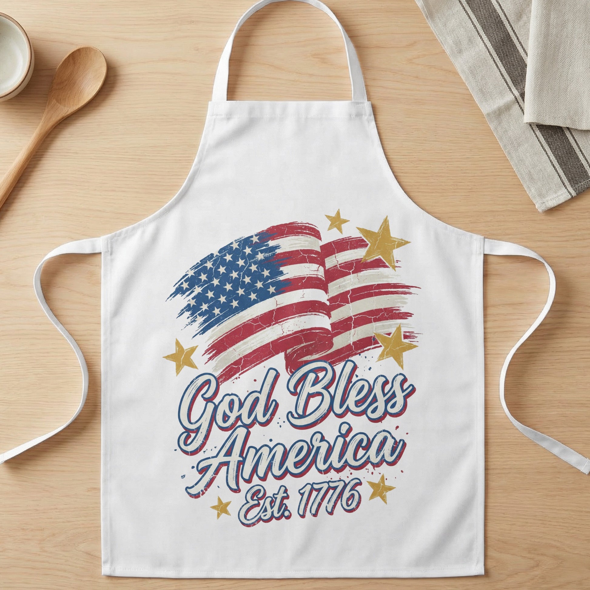 White apron with American flag graphic and "God Bless America Est. 1776" text.