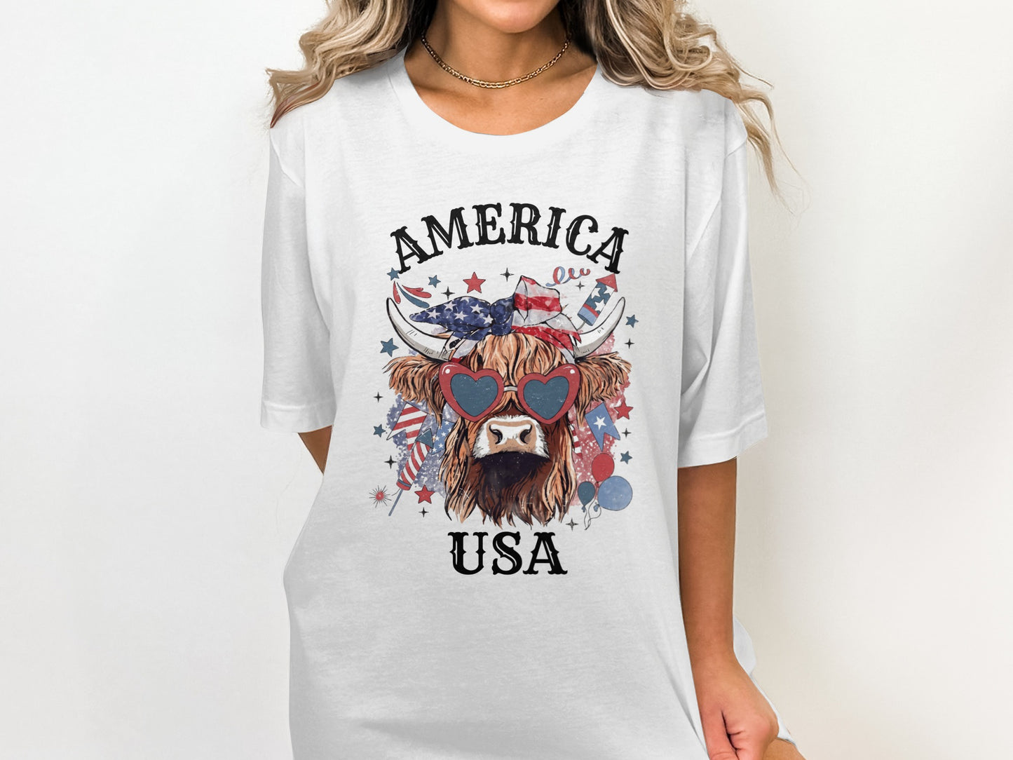 White t-shirt with a Highland cow wearing heart-shaped sunglasses with USA flag pattern.