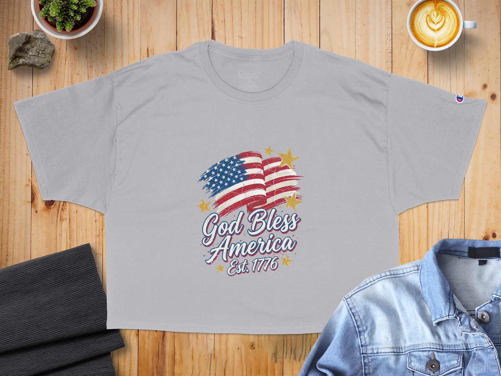 Grey t-shirt with distressed American flag graphic and "God Bless America Est. 1776" text.