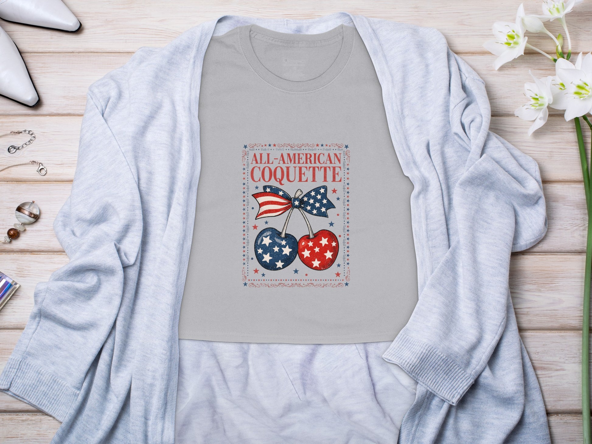 Grey t-shirt with "All-American Coquette" text, patriotic cherries and bow.