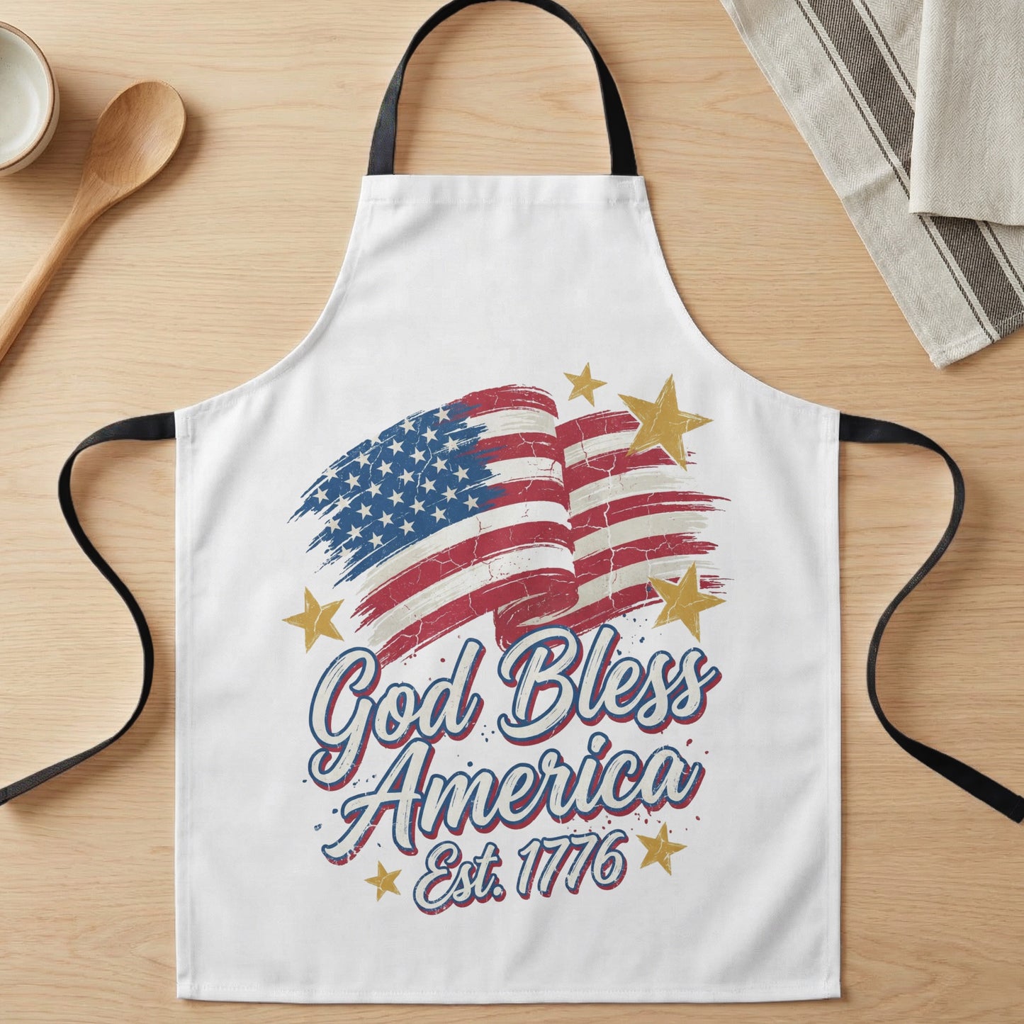 White apron with American flag graphic and "God Bless America Est. 1776" text.