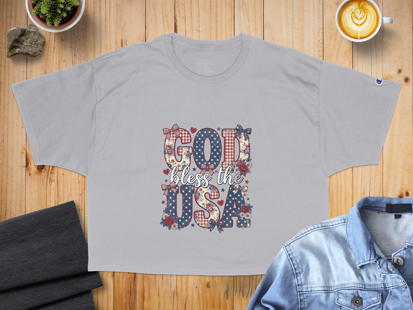 Gray t-shirt with "God bless the USA" graphic in patriotic patterns and floral accents.