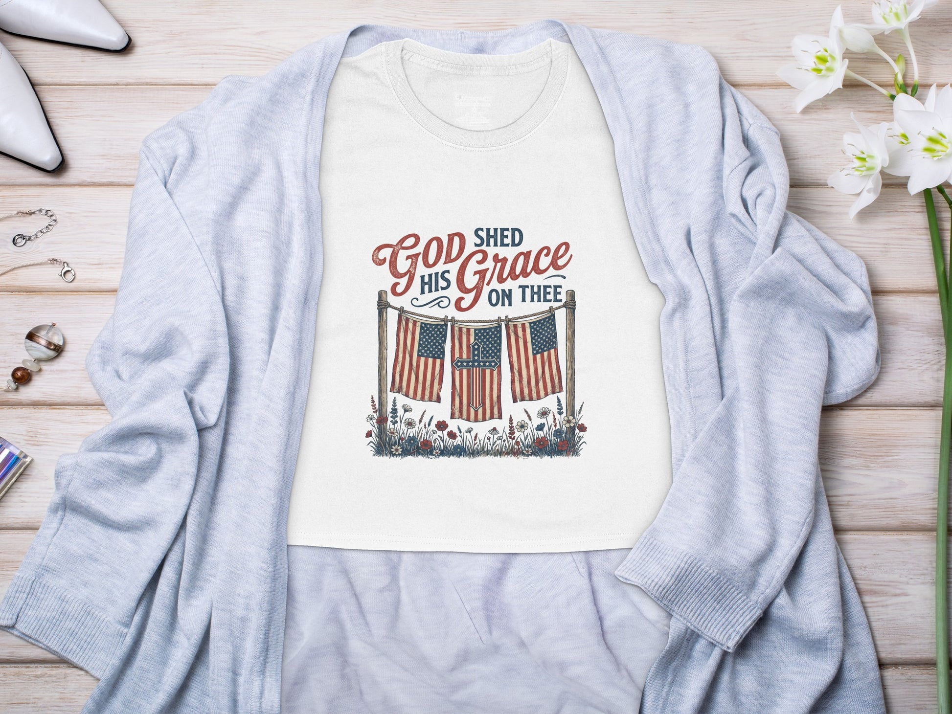 T-shirt with "God Shed His Grace on Thee" text over American flags and flowers.