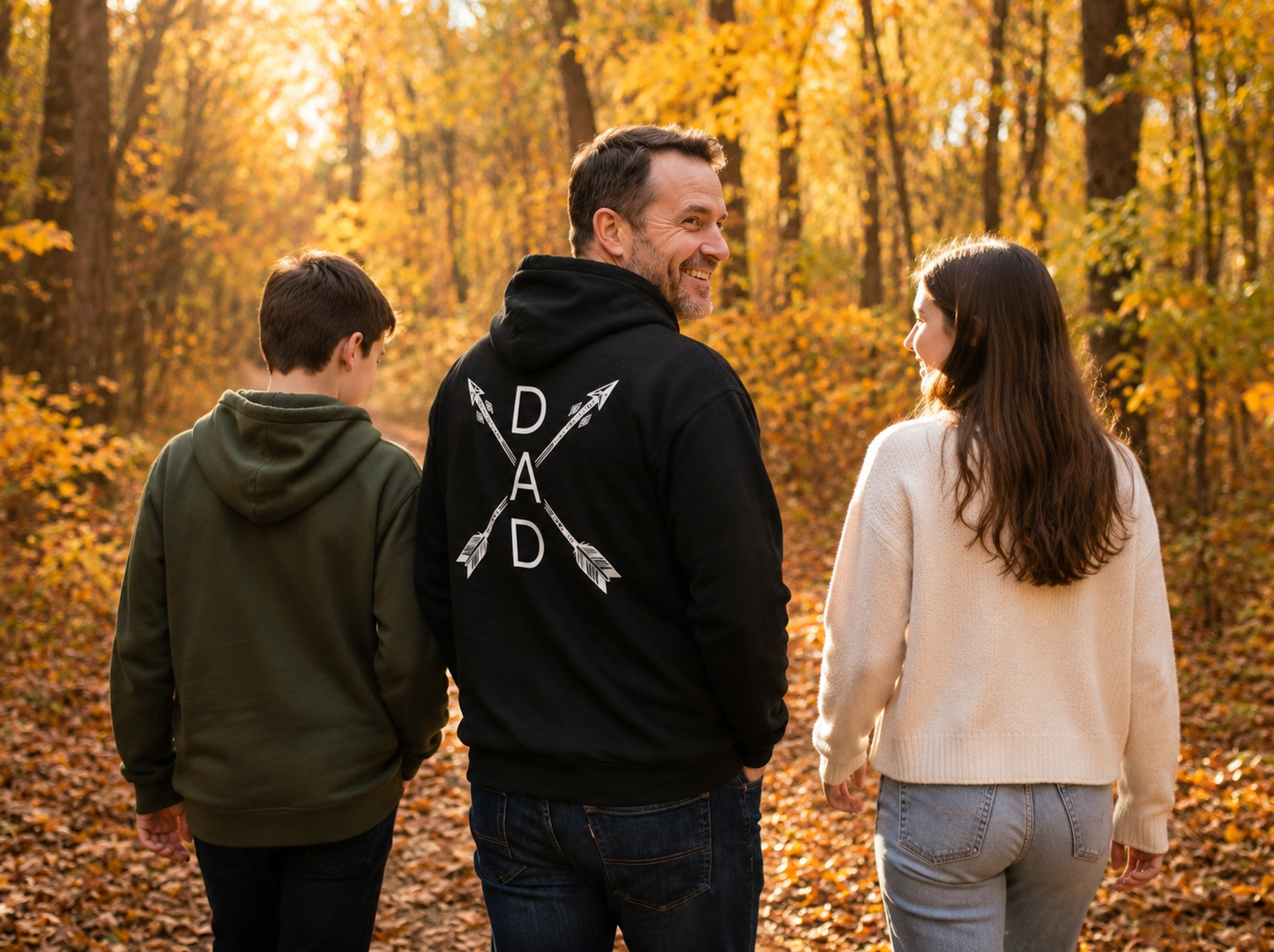 Dad wearing Heritage Arrow Dad Hoodie walking through autumn woods with family lifestyle image